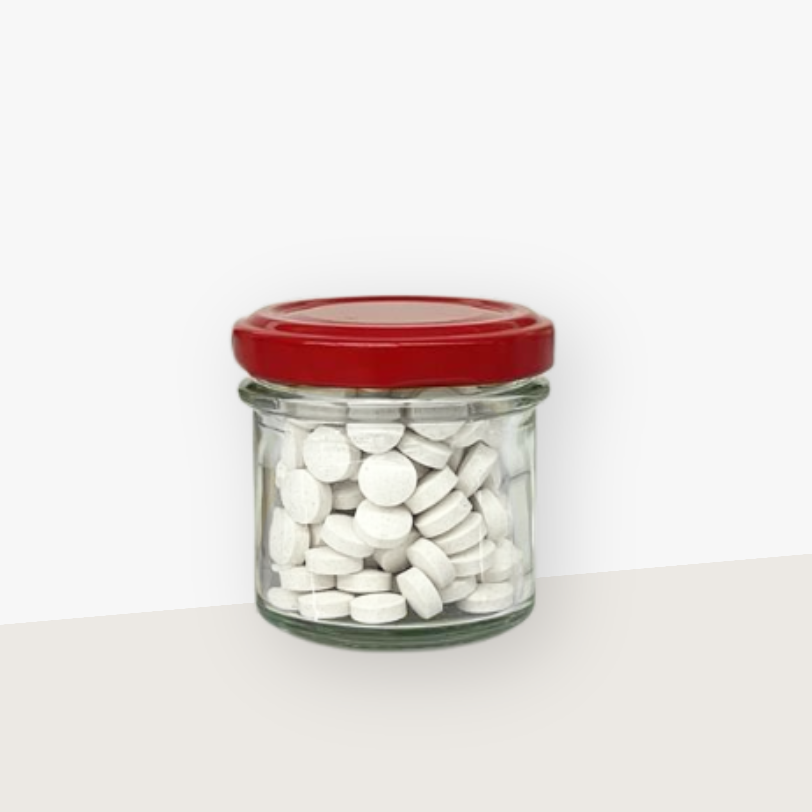 Ein Aufbewahrungsglas mit rotem Deckel gefüllt mit Denttabs in Zimtgeschmack. Der Hintergrund ist hell.
